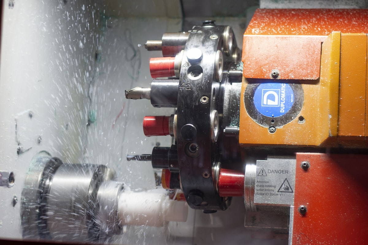 CNC vertical machining center milling a complex metal part with coolant flow